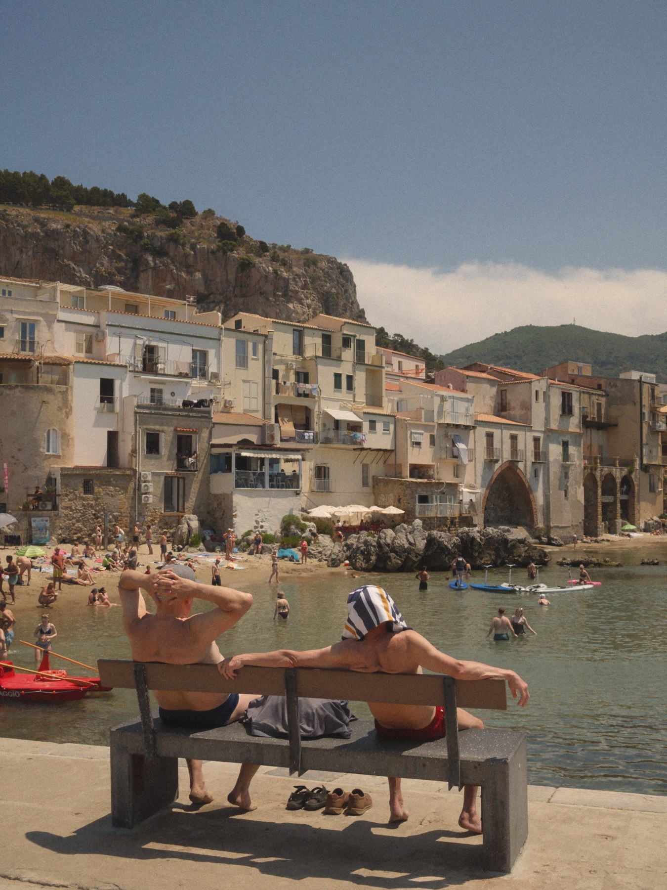 A sunbather stretched out beside a small harbour.