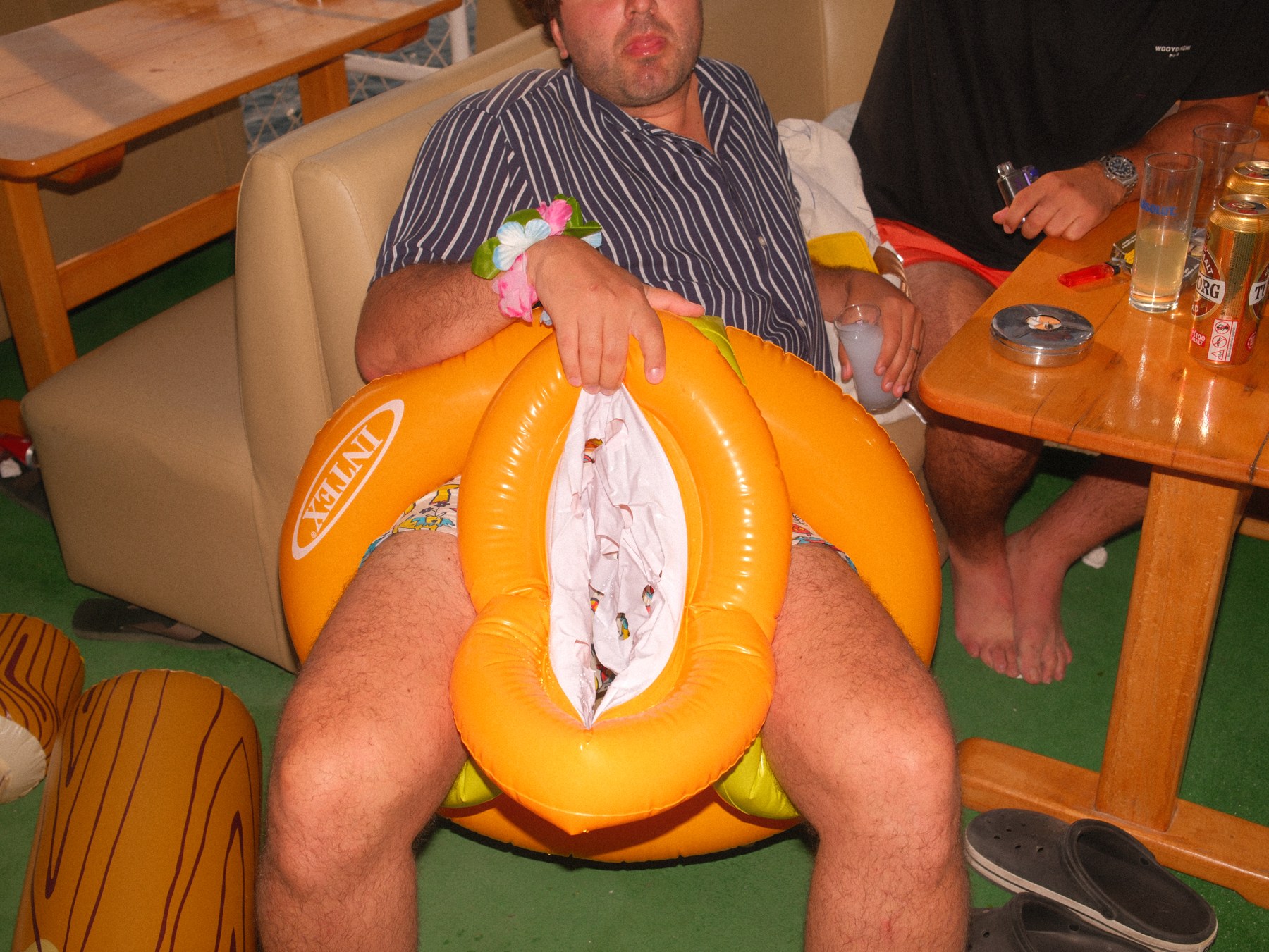 A seated man holding a bright orange inflatable ring.