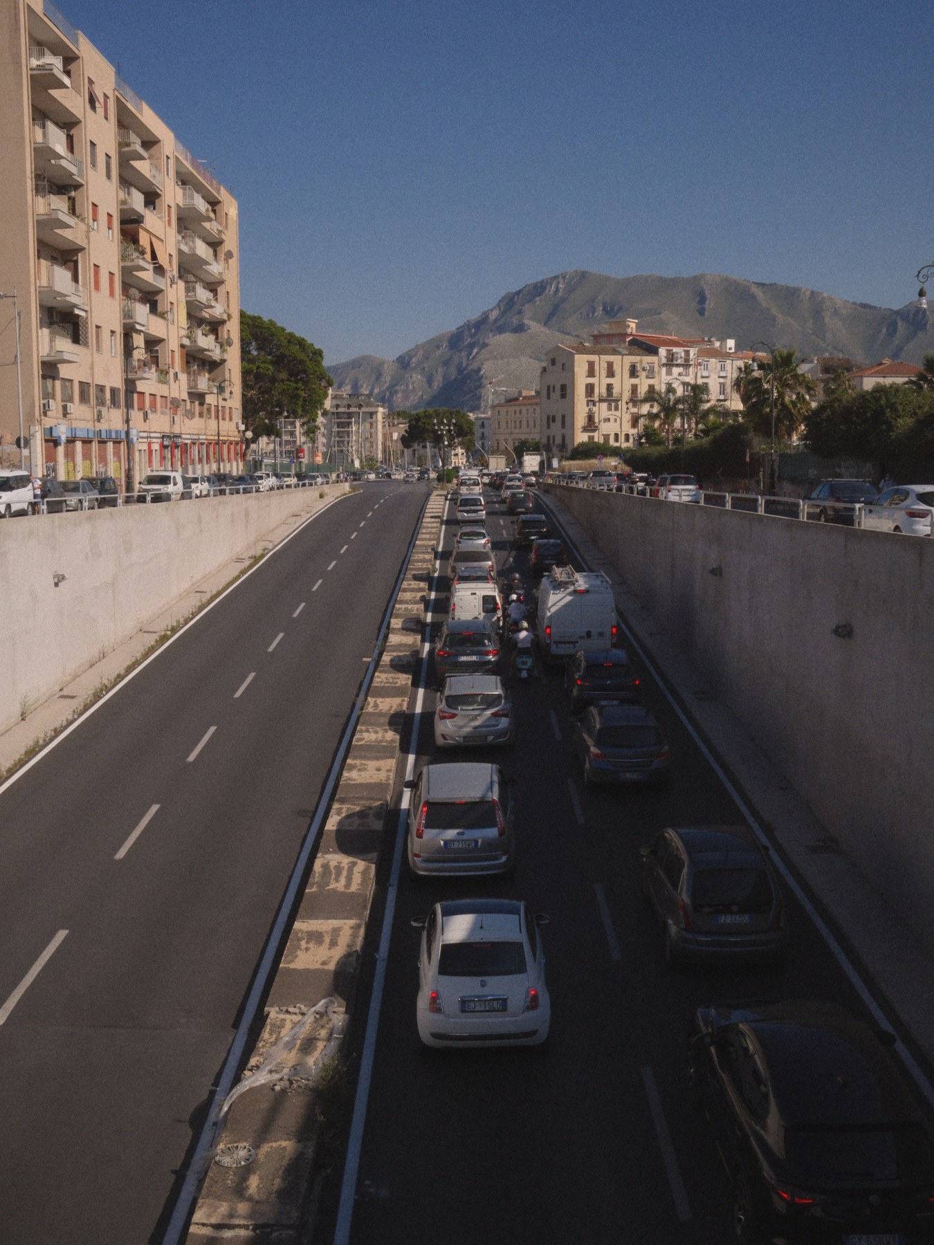 A road between buildings and mountains.
