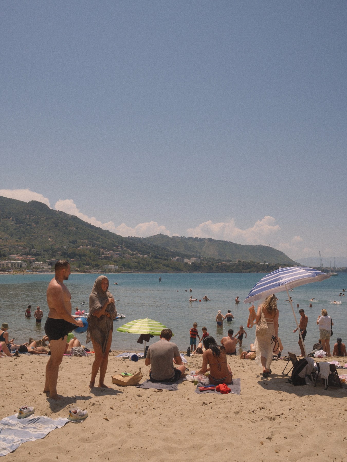 People gathering on a beach below the mountains.